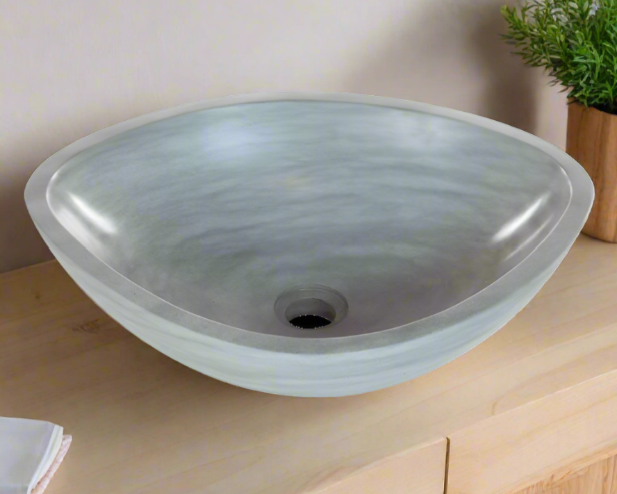Gray ceramic sink on a wooden vanity with a plant in the background